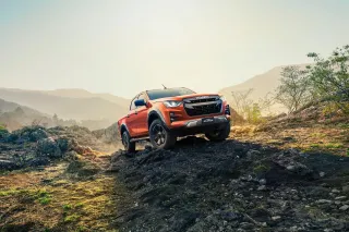 Oranžový pick-up Isuzu D-MAX v kopcovité krajině.
