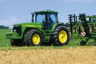 Zelený traktor John Deere 8400 na poli.