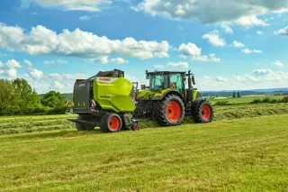 Traktor CLAAS s lisem VARIANT 500 při práci na louce.