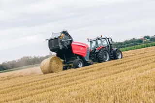 Traktor s lisem Massey Ferguson vytváří válcový balík na poli.