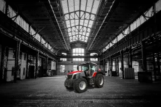 Červený traktor Massey Ferguson ve velké průmyslové hale.