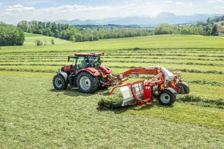 Traktor s pásovým shrnovačem Pöttinger MERGENTO VT 9220 na louce.
