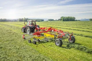 Traktor s dvourotorovým shrnovačem Pöttinger TOP 882 C na louce.