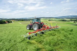 Traktor s desetirotorovým obracečem Pöttinger HIT V 11100 na louce.