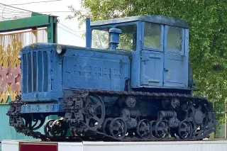 Historický modrý pásový traktor DT-54 vystavený venku.