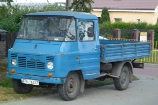 Modrý valníkový automobil FSC Żuk zaparkovaný u domu.