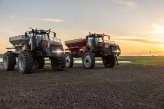 Dvě autonomní rozmetadla Case IH Trident na poli při západu slunce.