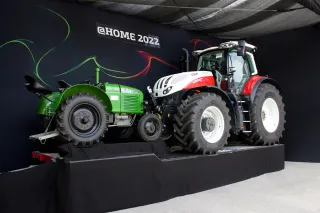 Historický zelený traktor Steyr vedle nového traktoru na výstavě.