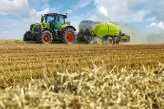 Traktor s lisem CLAAS QUADRANT při práci na poli.