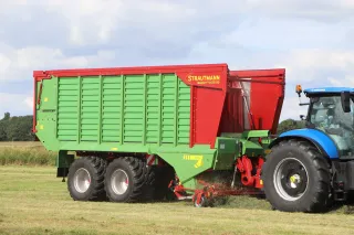Modrozelený traktor se sběracím vozem Strautmann Magnon CFS 8.
