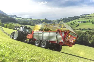 Traktor se senážním vozem Pöttinger BOSS MASTER na louce.