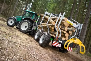 Traktor s vyvážecí soupravou naloženou dřevem v lese.