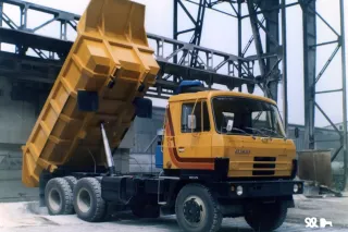 Žlutý sklápěcí nákladní vůz Tatra 815 se zdviženou korbou.