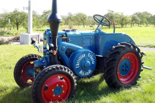 Historický modrý traktor Lanz Bulldog s červenými koly.