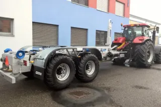 Traktor s kontejnerovým nosičem CHARVÁT CTS před budovou.