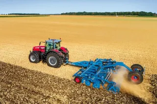 Červený traktor s modrým diskovým podmítačem Lemken Rubin 10 na poli.