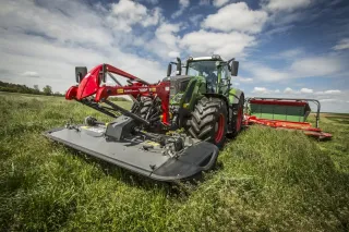 Traktor Fendt s čelním žacím strojem Fella při sečení louky.