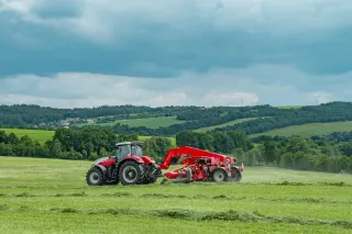 Červený traktor s pásovým shrnovačem SIP AIR 900 T při sklizni píce.