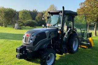 Tmavý traktor Carraro Agricube Pro stojí na trávníku.