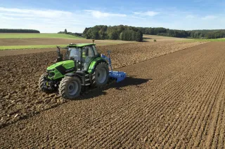 Zelený traktor Deutz-Fahr 6.4 při práci na poli.