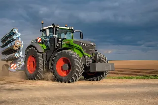 Velký zelený traktor Fendt s červenými koly na poli.