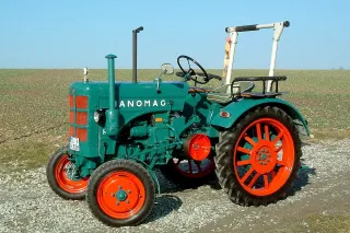 Historický zelený traktor Hanomag s oranžovými koly.
