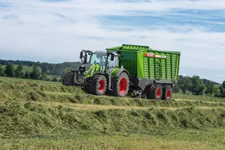 Traktor Fendt se zeleným senážním vozem Tigo při sklizni píce.