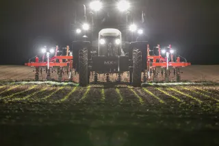 Traktor s meziřádkovou plečkou Lemken Steketee v noci na poli.