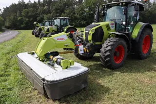 Traktory CLAAS se žacími stroji při ukázce na louce.