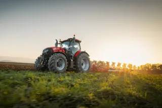 Červený traktor Case IH Puma 260 při práci na poli za západu slunce.
