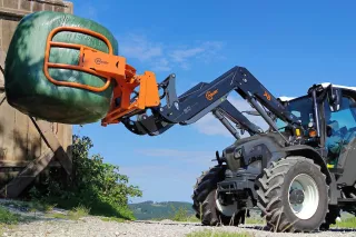 Traktor s čelním nakladačem HAUER zvedá balík.
