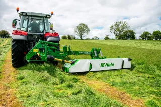 Traktor s bočním žacím strojem McHale při sečení trávy.