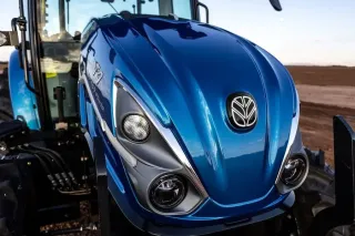 Detail přední části modrého traktoru New Holland.