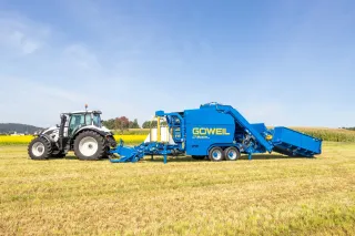 Traktor s modrým lisovacím a ovíjecím strojem Göweil na poli.