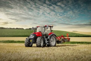 Červený traktor Case IH Vestrum CVXDrive s připojeným nářadím na poli.