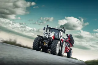 Traktor Steyr Absolut CVT s připojeným nářadím na silnici.