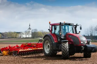Traktor Valtra s diskovým podmítačem na poli.