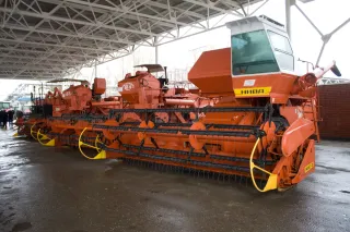 Oranžová sklízecí mlátička Niva SK-5 vystavená pod přístřeškem.