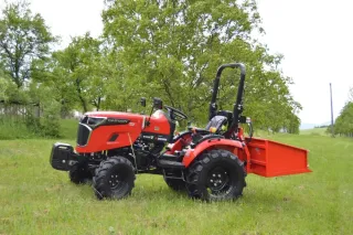 Červený malotraktor Captain s vlečkou na travnaté ploše.