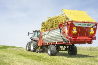 Traktor táhne senážní vůz Pöttinger BOSS 3000 s nákladem píce.