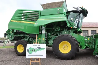 Zelená sklízecí mlátička John Deere řady T vystavená venku.