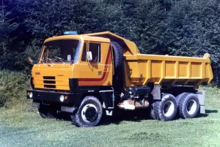Žlutý sklápěč Tatra 815 na travnaté ploše.