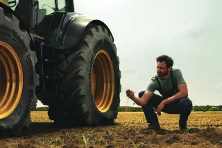 Muž u velkých traktorových pneumatik Continental na poli.