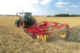 Traktor s červeným strojem Väderstad při zpracování pole.