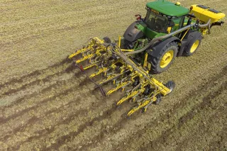 Traktor s pásovým kypřičem BEDNAR pracuje na poli.