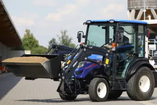 Modrý komunální traktor Iseki s čelním nakladačem.