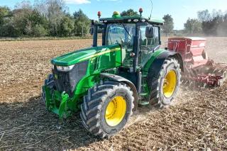 Zelený traktor s velkými pneumatikami Alliance pracuje na poli.