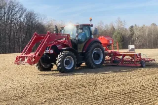 Traktor Case IH s lučním secím strojem Einböck na poli.
