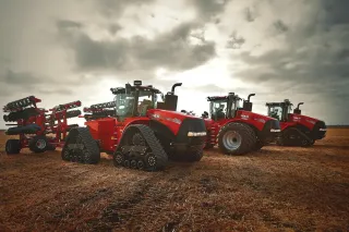 Tři červené traktory Case IH Steiger a Quadtrac na poli.