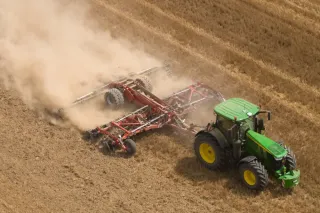 Traktor s diskovým podmítačem Grégoire Besson na poli.